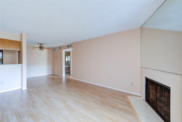 a view of an empty room with wooden floor fireplace and a window