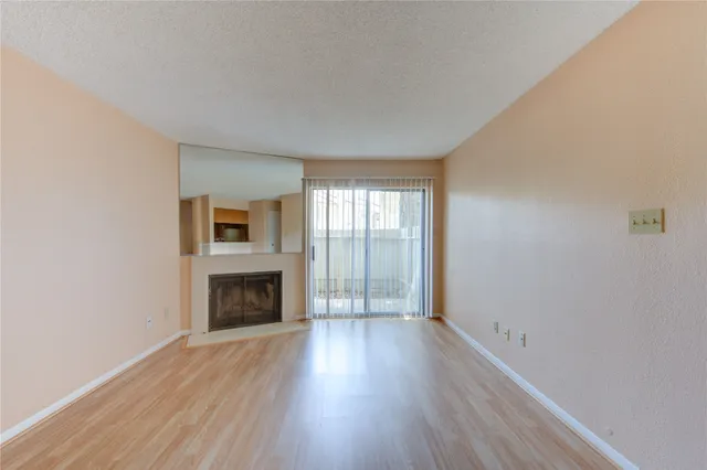 an empty room with wooden floor fireplace and windows