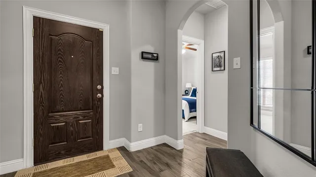 a view of a hallway with wooden floor and a bathroom