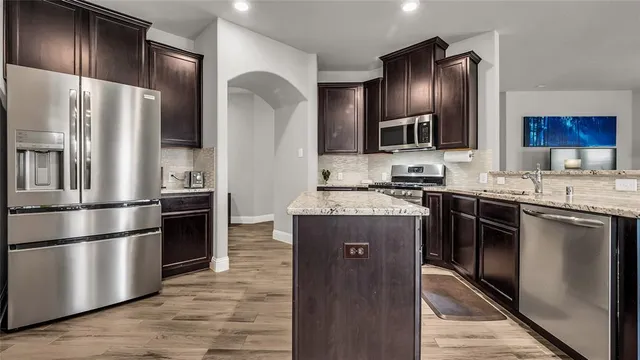 a kitchen with stainless steel appliances granite countertop a refrigerator a stove a sink and a refrigerator