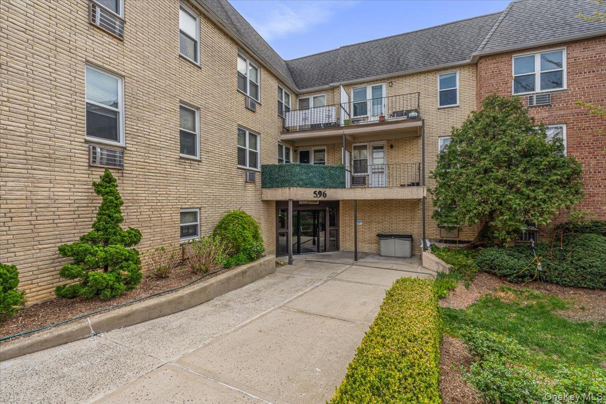 a front view of a house with garden and plants