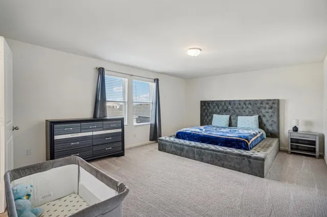 a spacious bedroom with a bed and a dresser