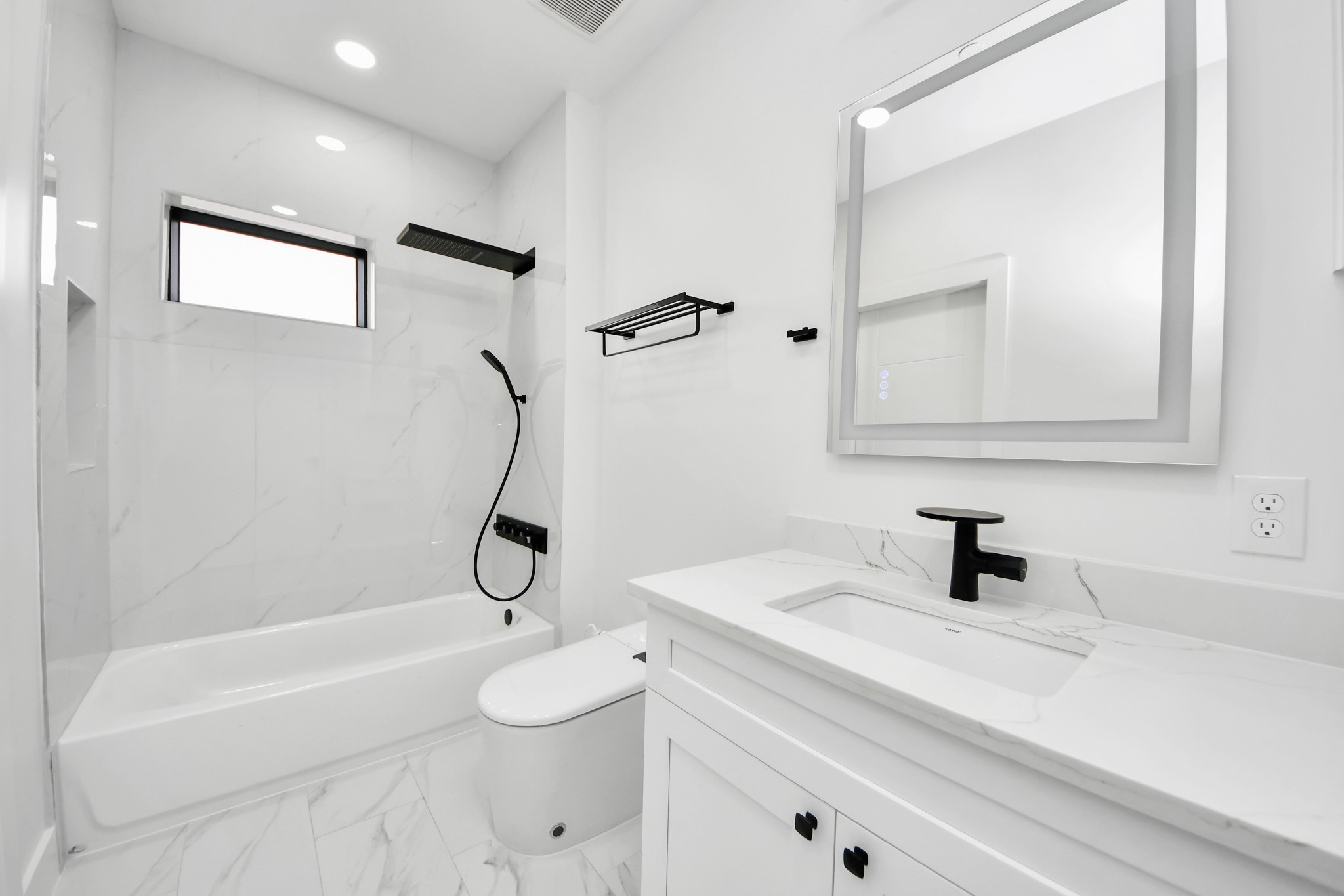 5115 Maple Street Bellaire, TX 77401 - Photo 40 of 45 Sleek white and black secondary bathroom featuring a sizable tub, LED mirror, and a smart toilet!