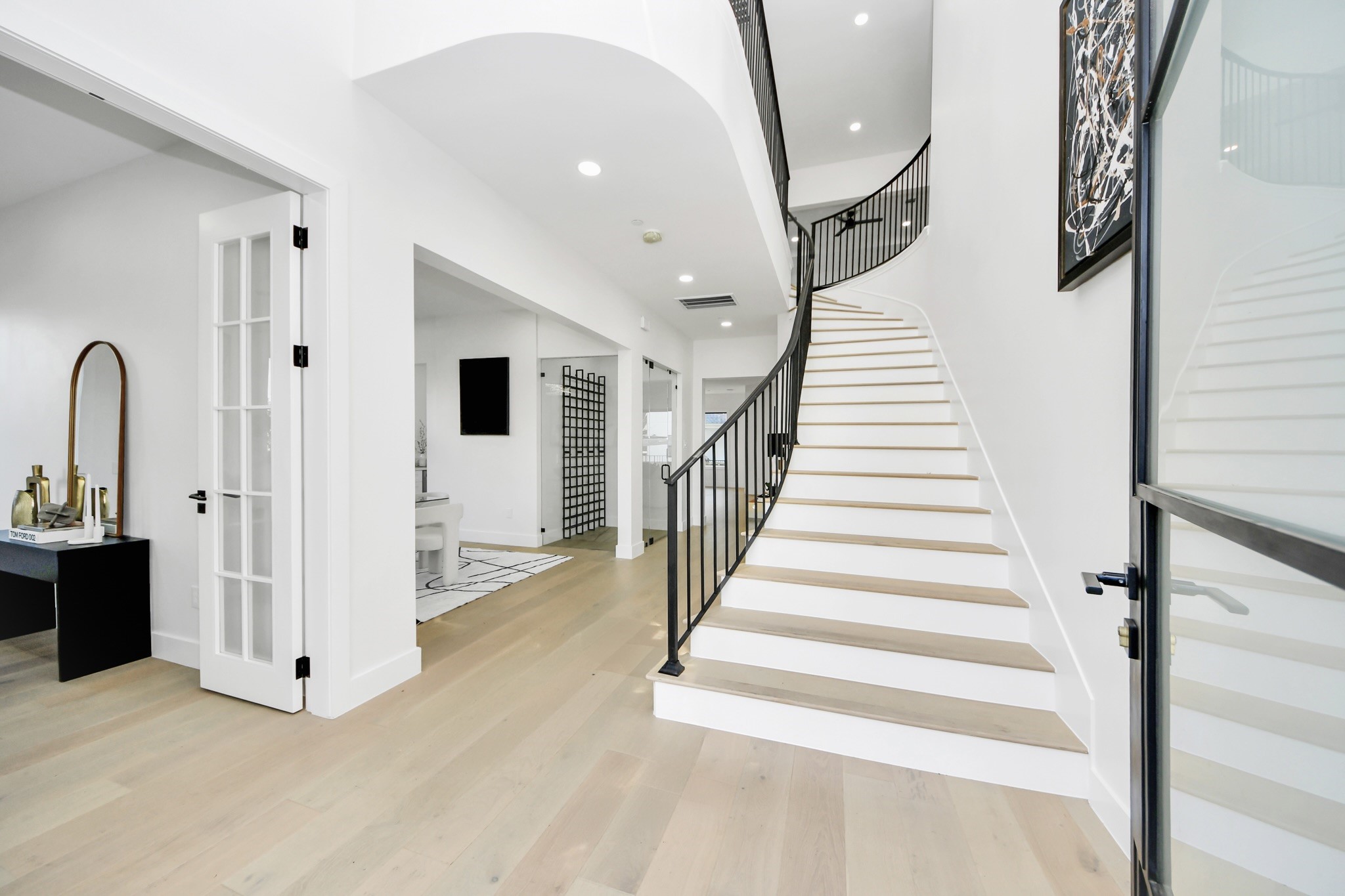 5115 Maple Street Bellaire, TX 77401 - Photo 5 of 45 Light-filled foyer featuring wide-plank flooring and a dramatic curved staircase that sets an elegant tone for the home.