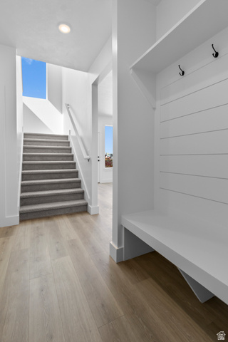 248 West 2920th Street South Logan, UT 84321 - Photo 25 of 47 Wood-finish flooring, built-in mudroom bench with shiplap backing, integrated coat hooks, recessed ceiling lighting, and a carpeted staircase