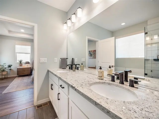 a bathroom with a granite countertop double vanity sink and a mirror