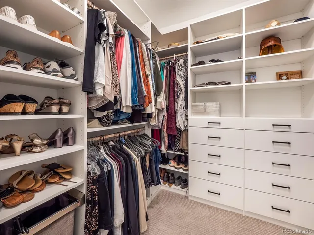 a view of walk in closet with clothes and shoes