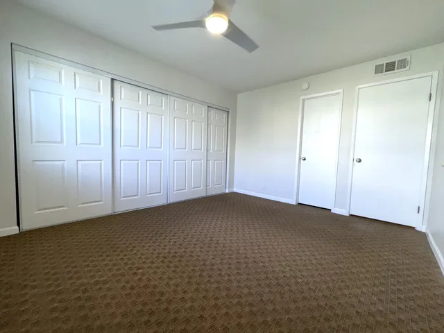 a view of an empty room and chandelier fan