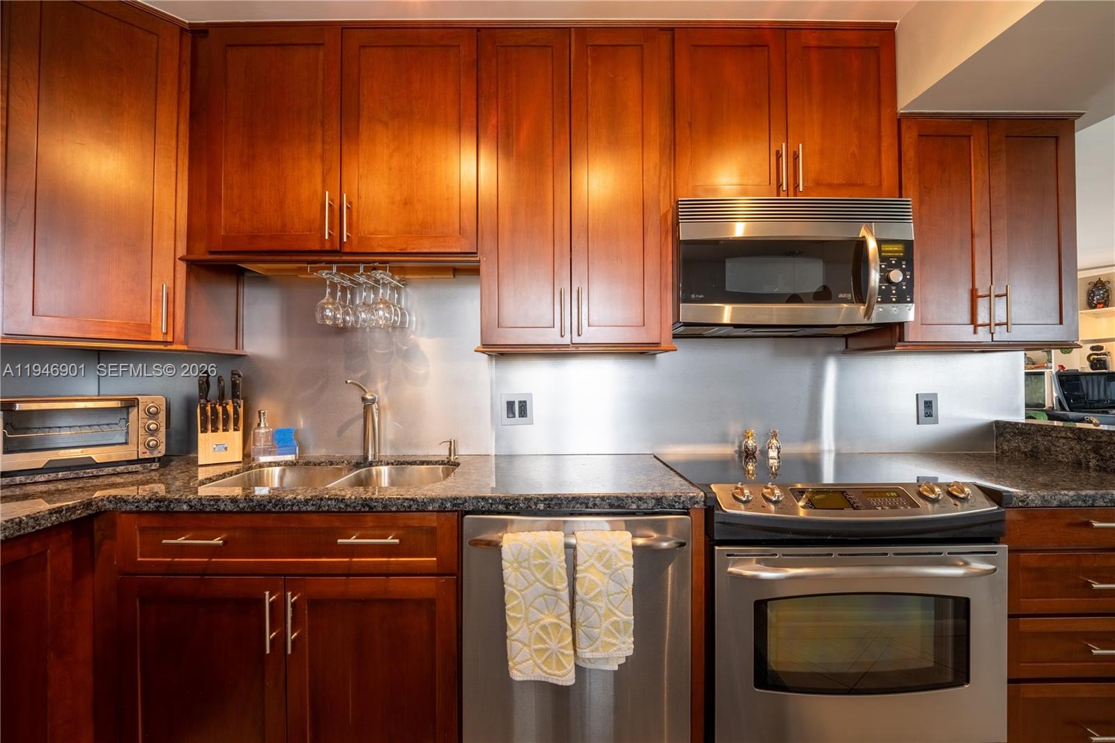 100 Ocean Trail Way, Unit 408 Jupiter, FL 33477 - Photo 29 of 46 a kitchen with stainless steel appliances granite countertop wooden cabinets and a stove top oven
