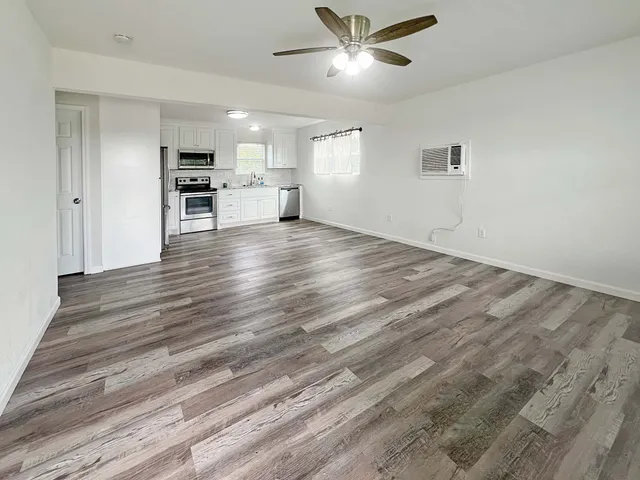 a view of empty room with wooden floor and window