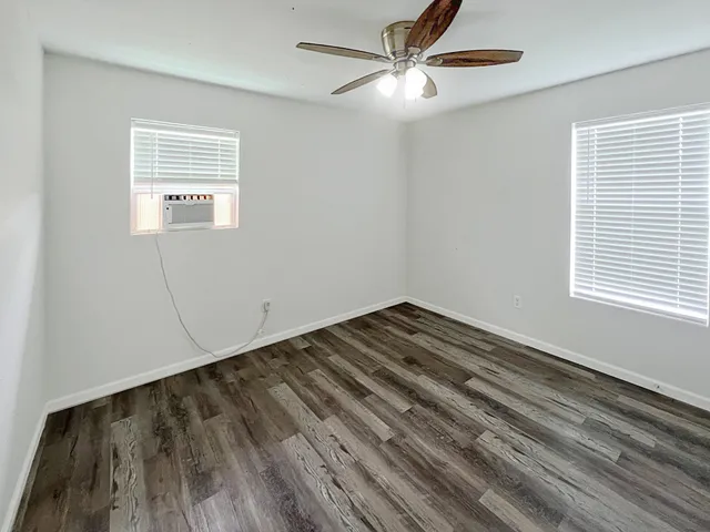 a view of empty room with wooden floor and fan
