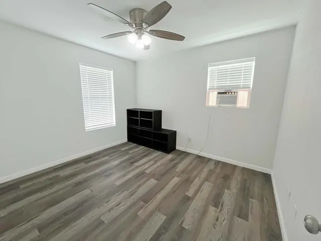 a view of empty room with wooden floor and fan