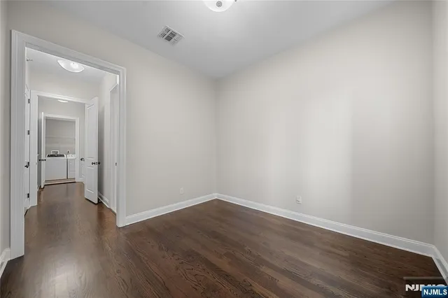an empty room with wooden floor cabinet and a bathroom