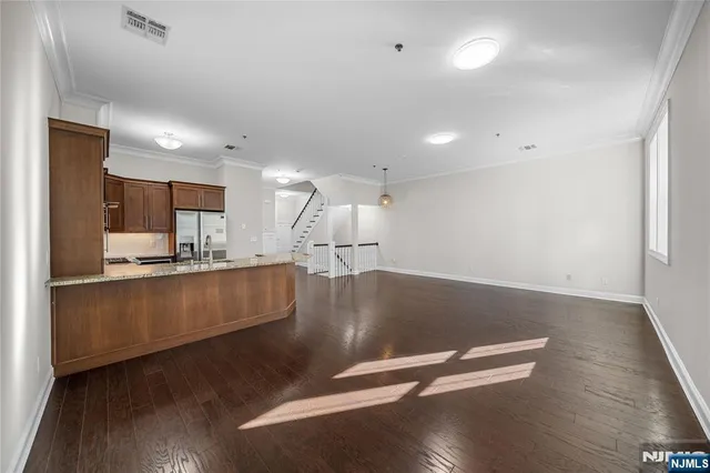 a view of a kitchen and an empty room with wooden floor