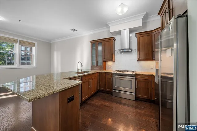 a kitchen with stainless steel appliances granite countertop a table chairs refrigerator and sink