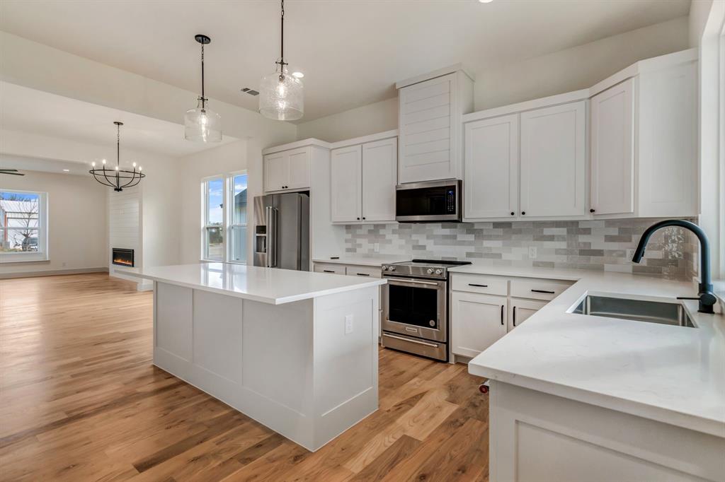 205 West 7th Street Justin, TX 76247 - Photo 14 of 35 a kitchen with kitchen island a white counter top space cabinets and stainless steel appliances