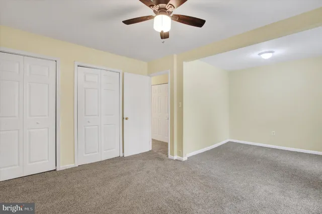 a view of an empty room and chandelier fan