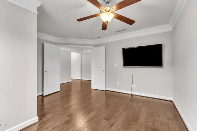 an empty room with wooden floor fan and windows