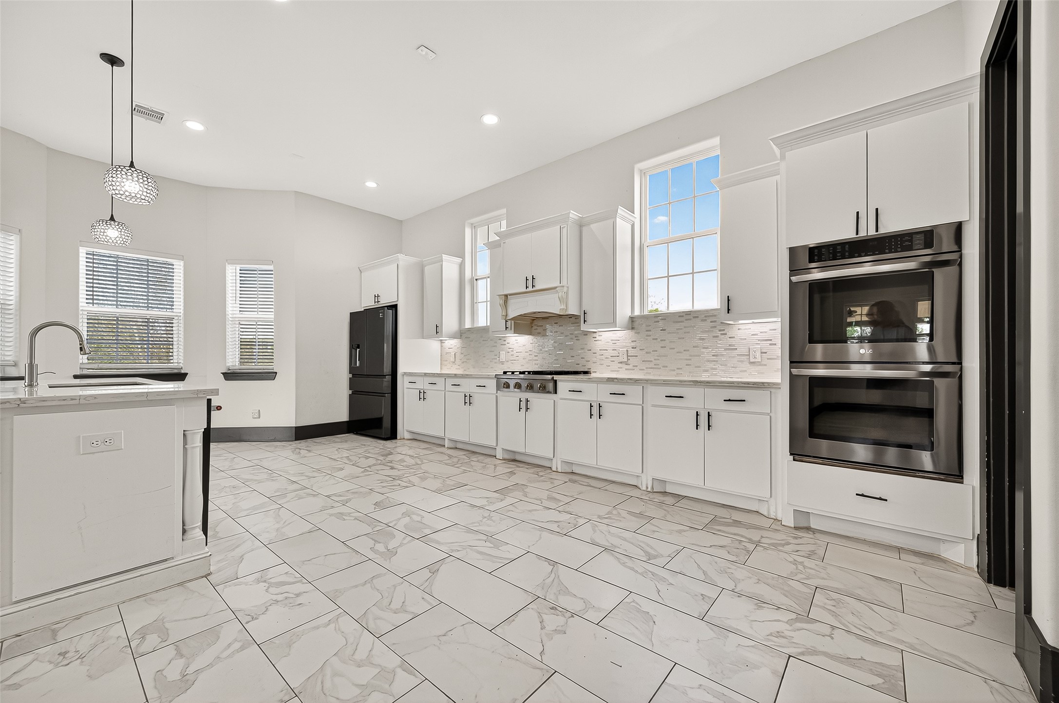 7915 Kirk Road Rosenberg, TX 77471 - Photo 14 of 28 This bright, modern kitchen features sleek white cabinetry, stainless steel appliances, and a spacious island with a sink. The tile flooring and ample natural light create an inviting atmosphere, perfect for cooking and entertaining.