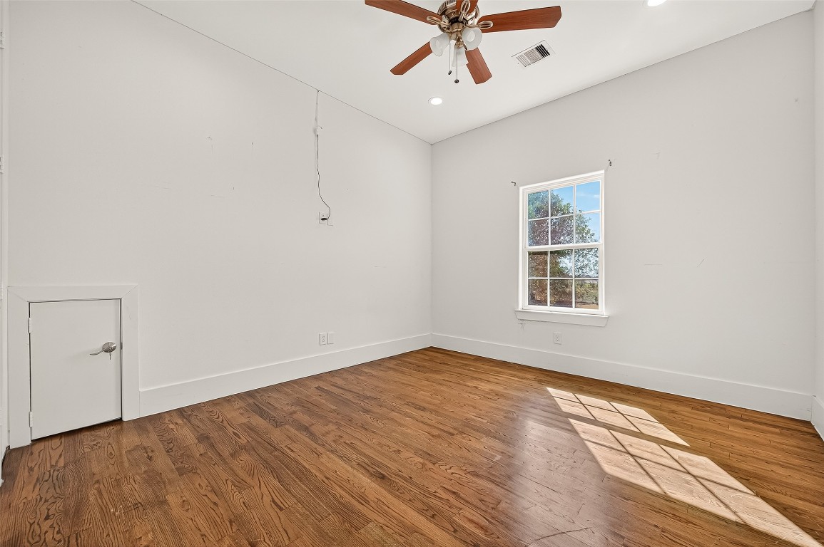 7915 Kirk Road Rosenberg, TX 77471 - Photo 16 of 28 This room features hardwood flooring, neutral walls, and a ceiling fan with wooden blades. It has two doors, one leading to a hallway with a railing, offering a bright and versatile space.
