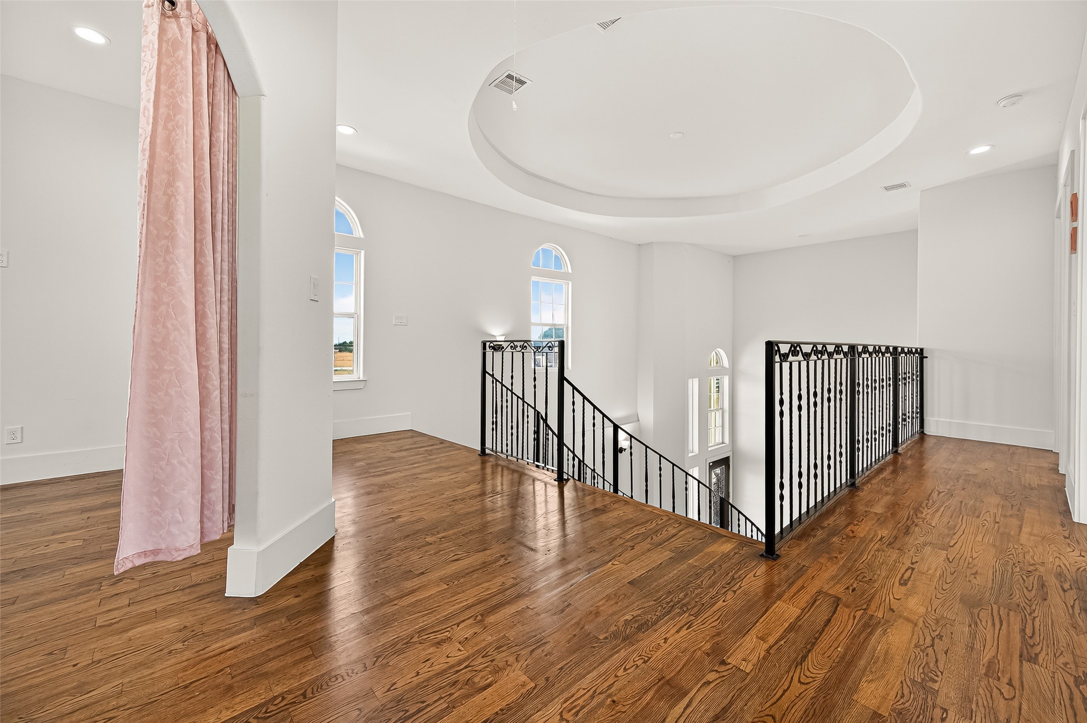 7915 Kirk Road Rosenberg, TX 77471 - Photo 23 of 28 This room features hardwood flooring, a ceiling fan, recessed lighting, and a built-in white cabinet. There's an open doorway with pink curtains leading to another area, creating a versatile space.