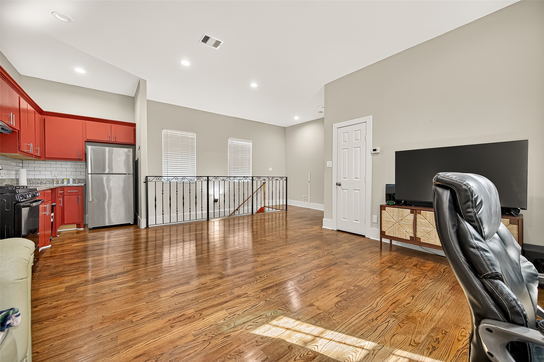 7915 Kirk Road Rosenberg, TX 77471 - Photo 28 of 28 This kitchen features vibrant red cabinets, a sleek black gas stove, stainless steel refrigerator, and a classic white subway tile backsplash. The wooden flooring adds warmth to the space.