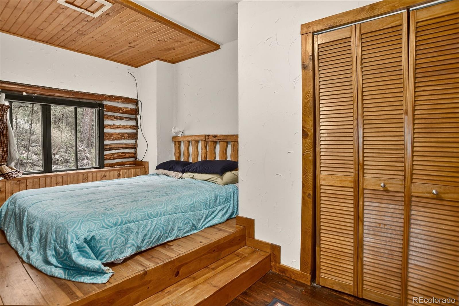 27403 Schuyler Gulch Road Pine, CO 80470 - Photo 21 of 40 a bed sitting in a bedroom next to a window