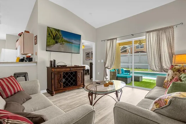 a view of a dining room and livingroom with furniture wooden floor a rug a chandelier and a mirror