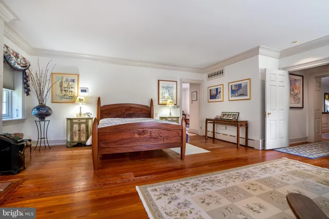 a bedroom with a bed a dresser and wooden floor