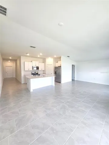 a large kitchen with kitchen island a stove a sink a refrigerator and white cabinets