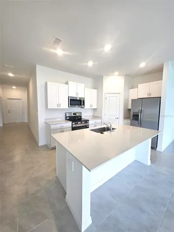 a kitchen with a sink a stove a microwave and white cabinets