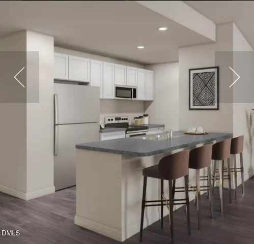 a kitchen with stainless steel appliances granite countertop a dining table chairs refrigerator and sink