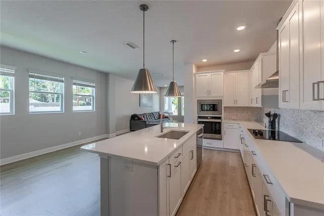 a large kitchen with stainless steel appliances kitchen island granite countertop a sink and a refrigerator