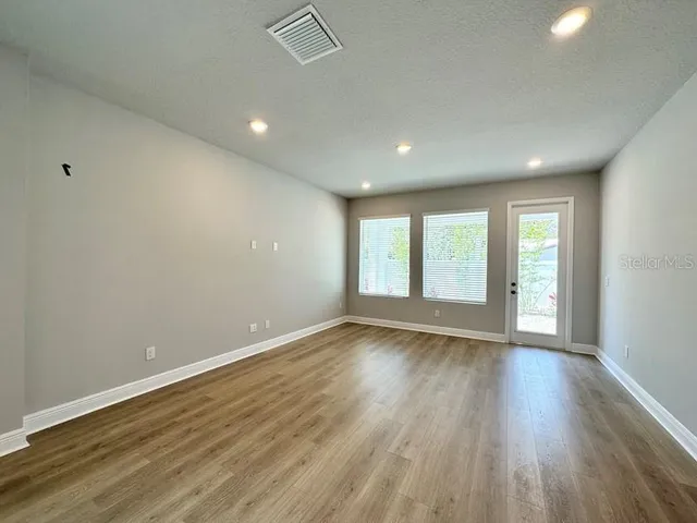 a view of an empty room with wooden floor and a window