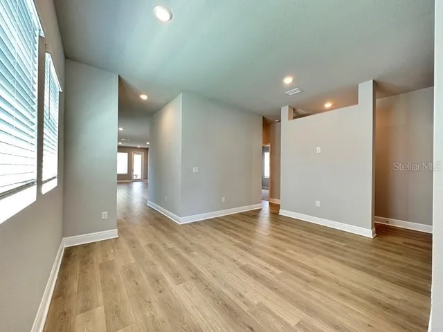 an empty room with wooden floor and windows