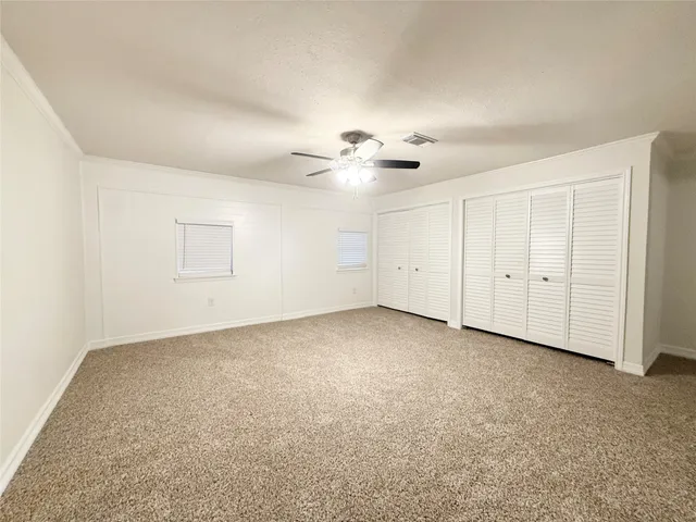 an empty room with a ceiling fan and windows