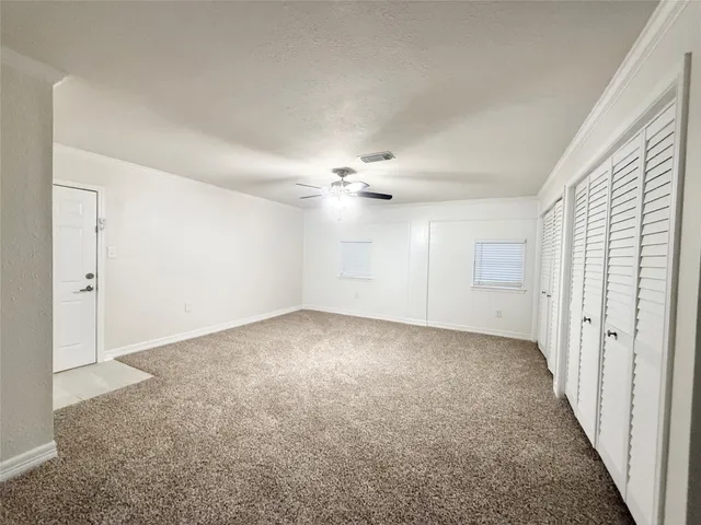 an empty room with a ceiling fan and carpet