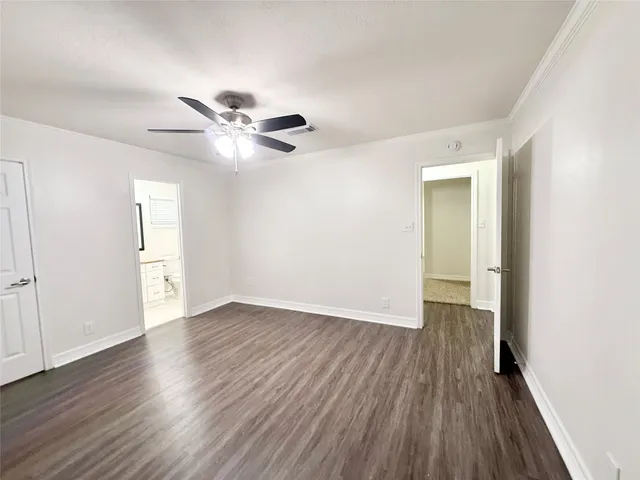 an empty room with wooden floor and a ceiling fan