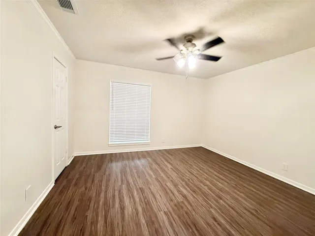 an empty room with wooden floor fan and windows