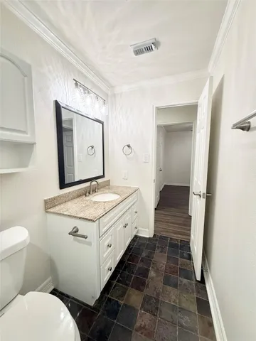 a bathroom with a granite countertop toilet sink and mirror