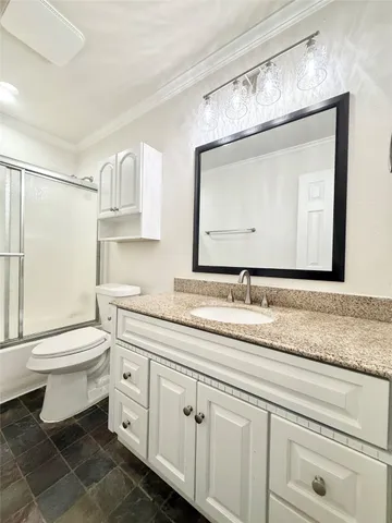 a bathroom with a granite countertop toilet sink and mirror