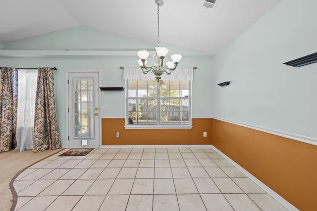a view of an empty room with window and chandelier