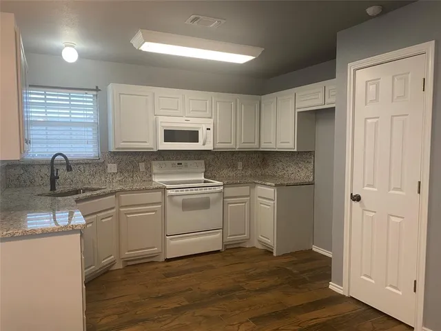 a kitchen with granite countertop white cabinets and white appliances