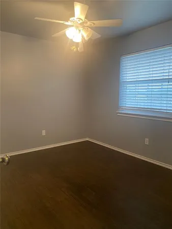 an empty room with a fan & a window