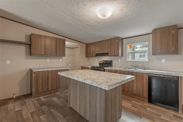 a kitchen with granite countertop a stove top oven a sink dishwasher and a refrigerator with wooden floor