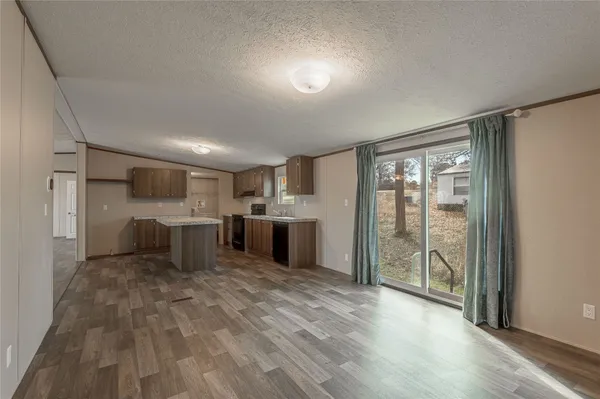 an empty room with wooden floor and windows with curtains