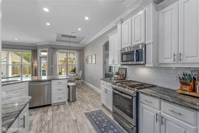 a kitchen with stainless steel appliances granite countertop a stove top oven a sink dishwasher and cabinets with wooden floor