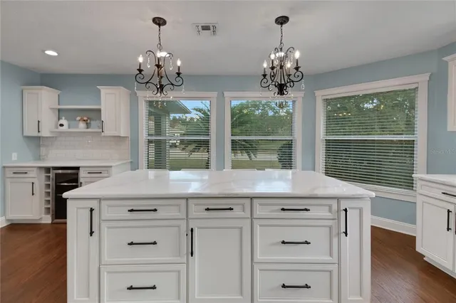 a dining hall with granite countertop a stove a sink dishwasher and a large mirror with wooden floor