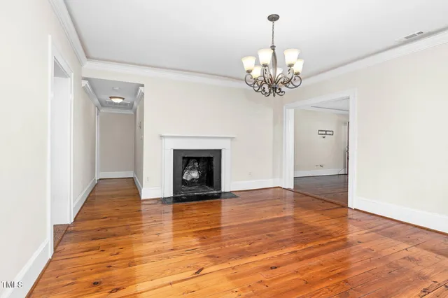a view of a livingroom with a chandelier fireplace and wooden floor