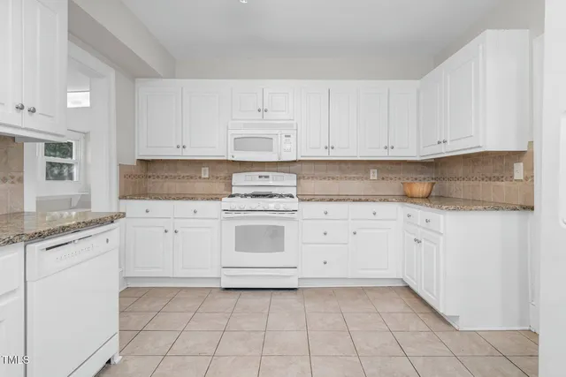 a kitchen with granite countertop white cabinets and white stainless steel appliances